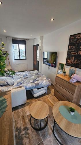 a room with a large bed and tables in it at comfortable studio in Bezons in Bezons