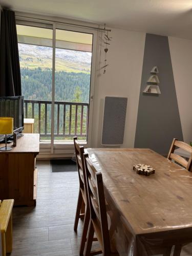 une salle à manger avec une table en bois et une grande fenêtre dans l'établissement Verseau Flaine Forêt, à Arâches-la-Frasse