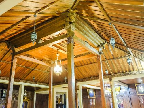a room with a wooden ceiling with lights at Pendhapa Art Space - PAS Limasan Homestay in Yogyakarta