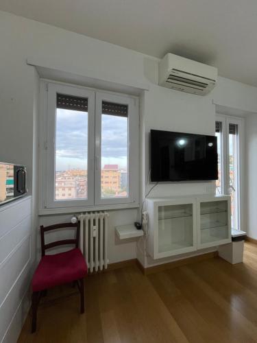 a living room with a television and a chair and windows at Casa Conca D Oro in Rome