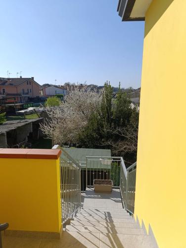 a yellow building with a stairway leading to a balcony at Alloggio La Goccia in Rosolina