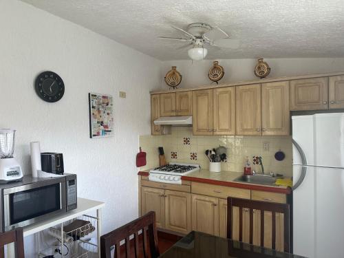 a kitchen with wooden cabinets and a white refrigerator at Villita en la floresta in Ajijic
