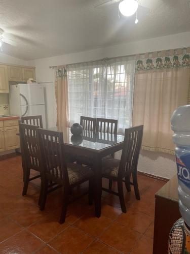 a kitchen with a dining table and chairs and a table with a bottle at Villita en la floresta in Ajijic
