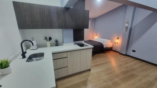 Una cocina con fregadero y una habitación con cama. en Casa 1982, en Manizales