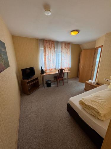 a bedroom with a bed and a desk and a television at Gasthof Hirschkeller in Göppingen