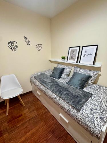 a bedroom with a bed and a white chair at Encanto del Norte in Villarcayo