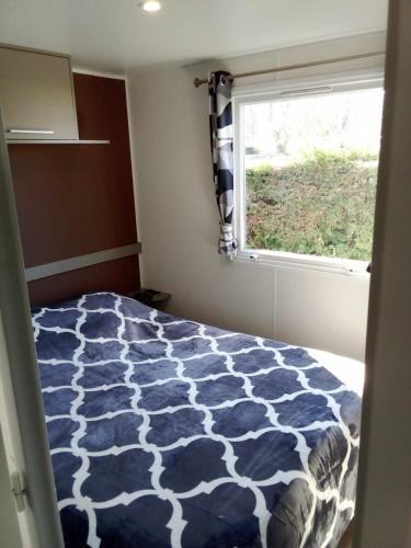 - une chambre avec un lit bleu et blanc et une fenêtre dans l'établissement TRES BEAU MOBIL HOME spacieux de 2ch - 6 personnes - LES CHARMETTES - La PALMYRE , Les MATHES, aux Mathes