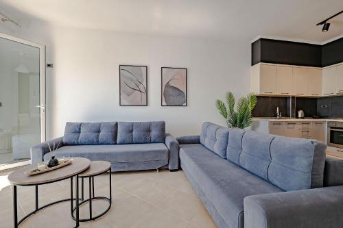 a living room with a blue couch and a table at Sunny Apts in Sarandë