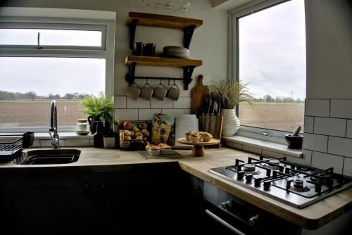 una cucina con piano cottura e lavandino e 2 finestre di Stylish Cottage near York a Rawcliffe