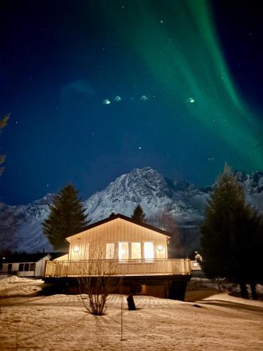 a house under the aurora with a mountain in the background at Linda`s house in Grashopen