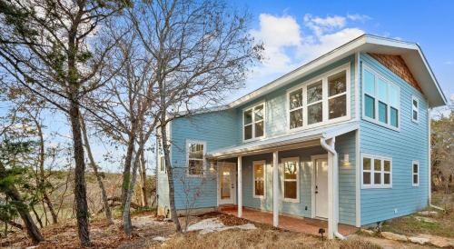 a blue house with trees in front of it at The Clifftop Perch, 70ft above the dry Blanco in Wimberley
