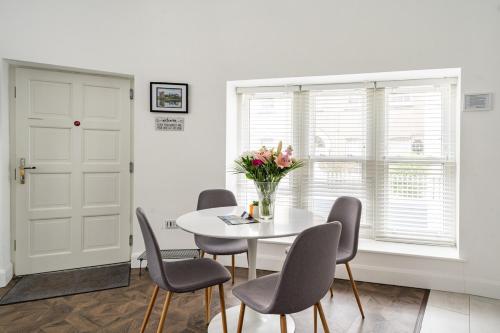 a white dining room with a white table and chairs at 1 Cathedral Place - Cathedral Townhouses Cobh in Cobh
