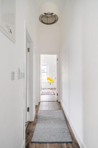 a hallway with a yellow chair in a white room at 1 Cathedral Place - Cathedral Townhouses Cobh in Cobh