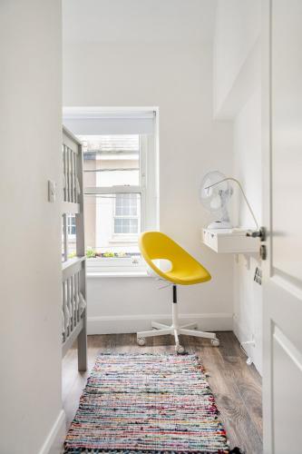 a yellow chair in a white room with a window at 1 Cathedral Place - Cathedral Townhouses Cobh in Cobh