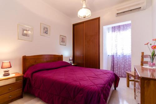 a bedroom with a purple bed and a window at Armação de Pêra Villa Hedwiges in Armação de Pêra
