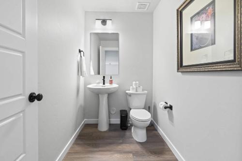 a white bathroom with a toilet and a sink at Spacious 6BR - Sleeps 22 - Game Room & Pool Access in Meridian