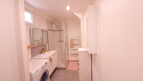 une salle de bain blanche avec un lavabo et une douche dans l'établissement Charmant logement proche gare, à Villemomble