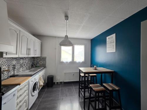 une cuisine avec des murs bleus et une table et des chaises dans l'établissement Appartement climatisé 4 personnes, à Sisteron