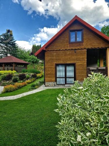 a wooden house with a green yard at Bieszczady Domek u Pączka in Polańczyk