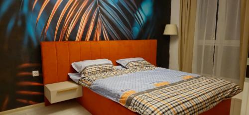 a bedroom with a bed with a orange headboard at M&EA apartments in Târgu-Mureş