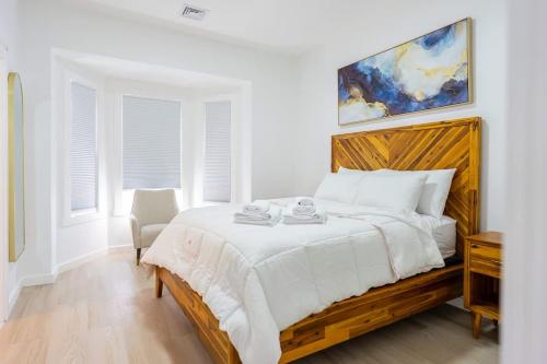 a white bedroom with a large bed with a wooden headboard at Luxury 2 Bed 2 Bath East Boston in Boston