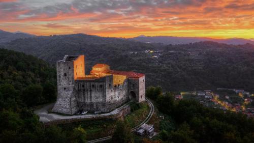 a building on a hill with a sunset in the background at Glamping Castel Dell'Aquila in Gragnola