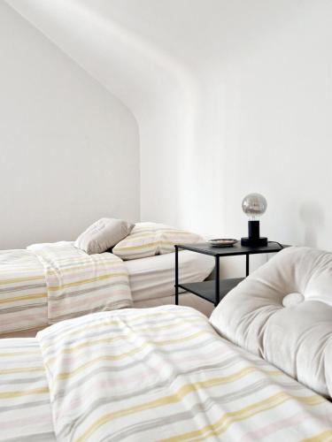 two beds in a white room with a table at La Maison des Petits Bonheurs in Rixheim