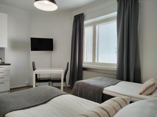 a bedroom with two beds and a desk and a window at Väinö Apartment 10 in Jyväskylä