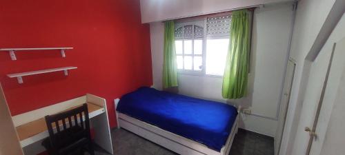 a small bedroom with a blue bed and a window at Hermosa casa, parrilla, aire libre, 8 personas in Buenos Aires