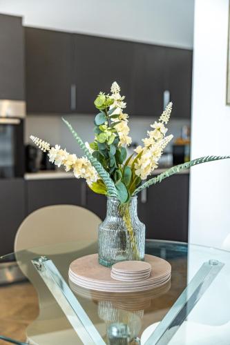 a vase with flowers sitting on a glass table at The Essex Apartments - Ashby House in Chelmsford