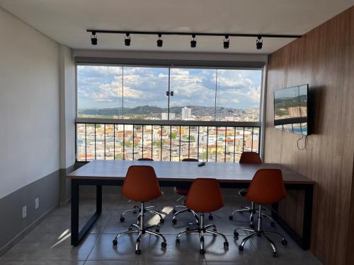 una sala conferenze con tavolo, sedie e una grande finestra di Loft Aconchego das Gerais Refúgio em São João del Rei a São João del Rei