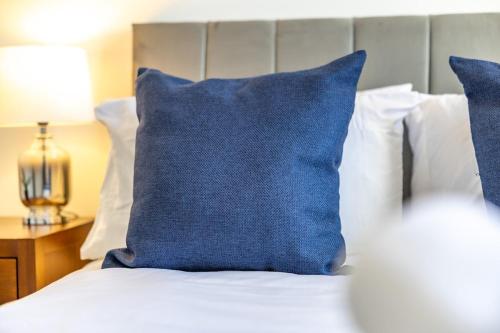 a blue pillow sitting on top of a bed at The Essex Apartments - Ashby House in Chelmsford
