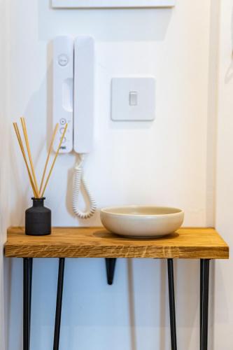 a table with a phone and a bowl on it at The Essex Apartments - Ashby House in Chelmsford