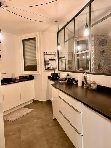 une cuisine avec des armoires blanches et un comptoir noir dans l'établissement cozy apartment - 9 min from Palace of Versailles, à Le Chesnay