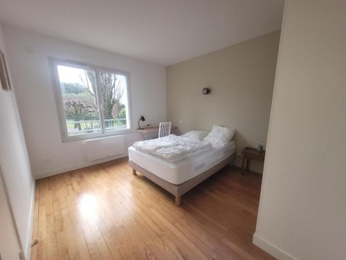 a white bedroom with a bed and a window at Appartement bord de mer, T4 in Saint-Nazaire