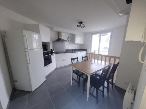 une cuisine avec une table et un réfrigérateur blanc dans l'établissement Appartement bord de mer, T4, à Saint-Nazaire
