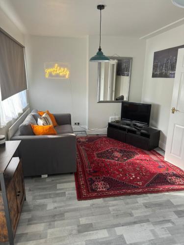 a living room with a couch and a red rug at 2 bedroom cosy flat in Norwood