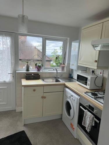 a kitchen with a sink and a washing machine at 2 bedroom cosy flat in Norwood