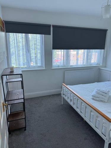 a bedroom with a bed and two large windows at 2 bedroom cosy flat in Norwood