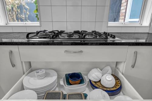 a kitchen with a stove and some plates and dishes at Cozy Home in Epsom in Auckland