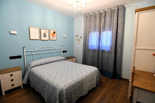 a blue bedroom with a bed and a window at En K La Cristi in Torija