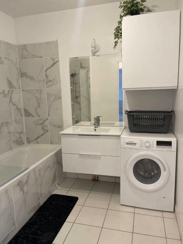 une salle de bain avec une machine à laver et un lavabo dans l'établissement Aeroport d'Orly , Parking privé, à Orly