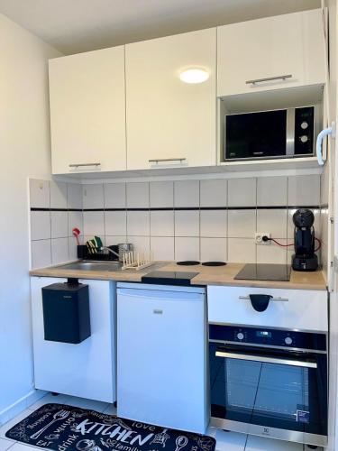 une cuisine avec des armoires blanches et un comptoir dans l'établissement Aeroport d'Orly , Parking privé, à Orly