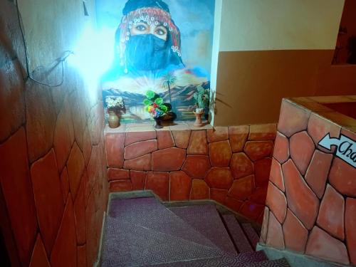 a bathroom with a painting of a person wearing a mask at Hotel Almanader in Boumalne