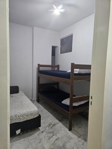 a room with two bunk beds and a bed at Apartamento para aproveitar a praia in Praia Grande