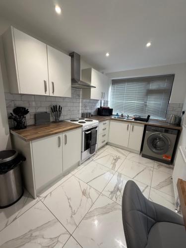a kitchen with white cabinets and a white tile floor at Contractor and Family, Private Detached Property DY5 in Brettell Lane