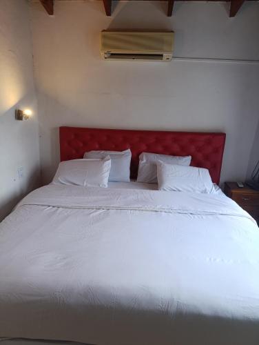 a large white bed with a red headboard in a room at Alojamiento walter in Ezeiza