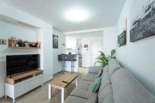 a living room with a couch and a tv at Ático Azucarera Torre del Mar in Torre del Mar