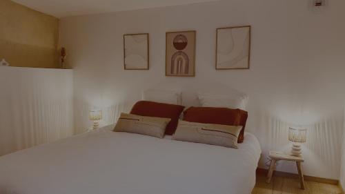 a bedroom with a white bed with three pictures on the wall at La Maison de Victoire et Alix in Pontrieux