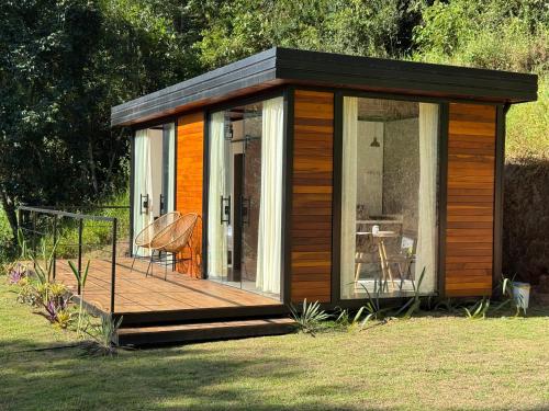 a wooden cabin with a deck in the grass at Mont Baron Bike Hotel Fazenda in Teresópolis